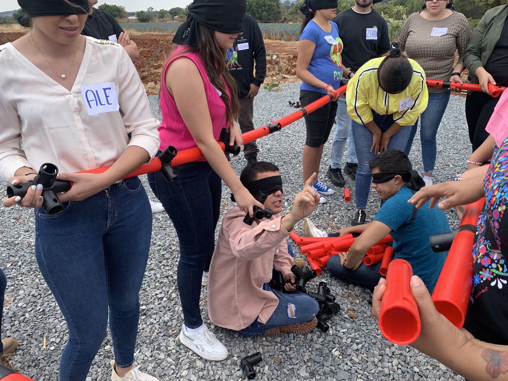 Equipo resolviendo una dinámica de colaboración con tubos y los ojos vendados